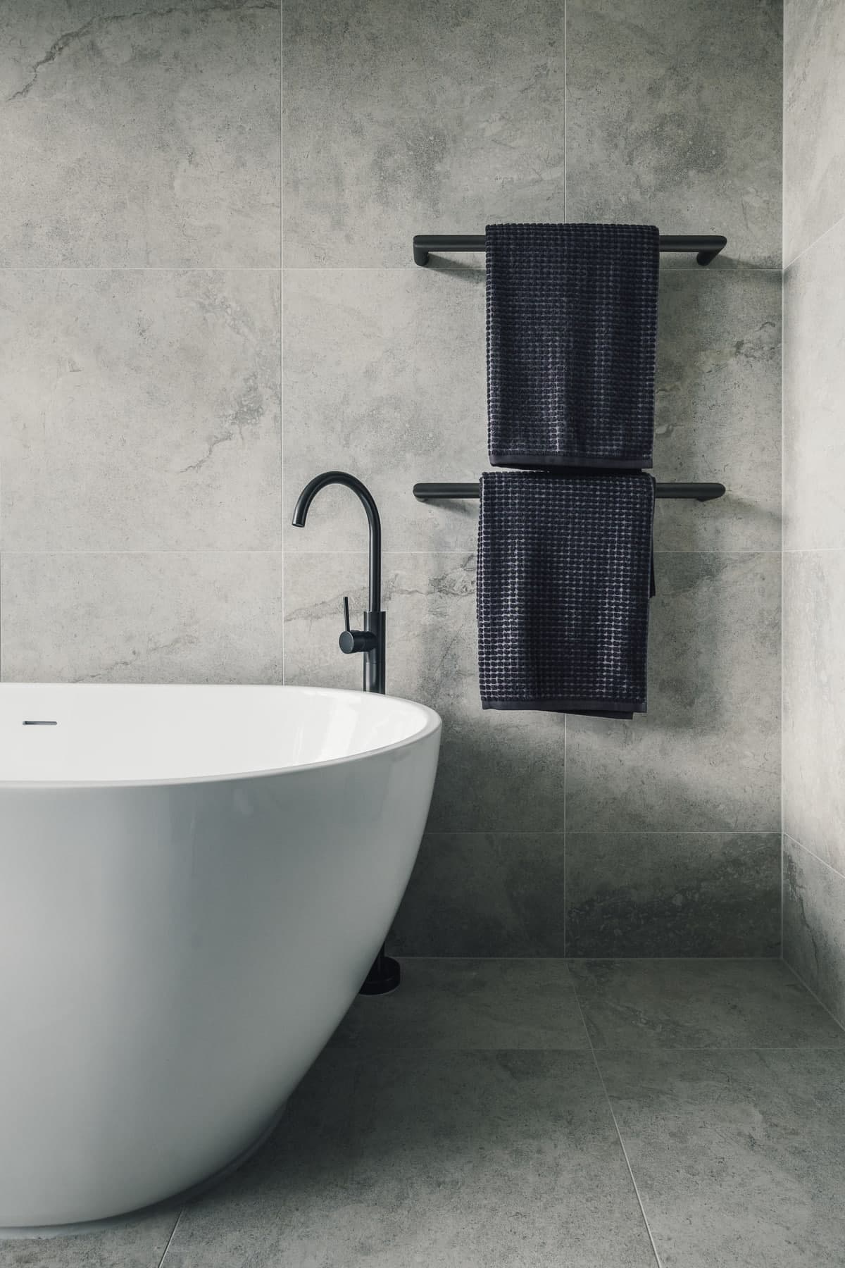 Modern and minimalist bathroom with freestanding bathtub and black matte faucet.