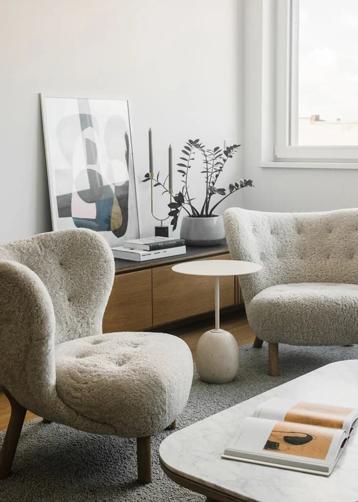 Modern cozy living room with tufted armchairs and light wood accents.