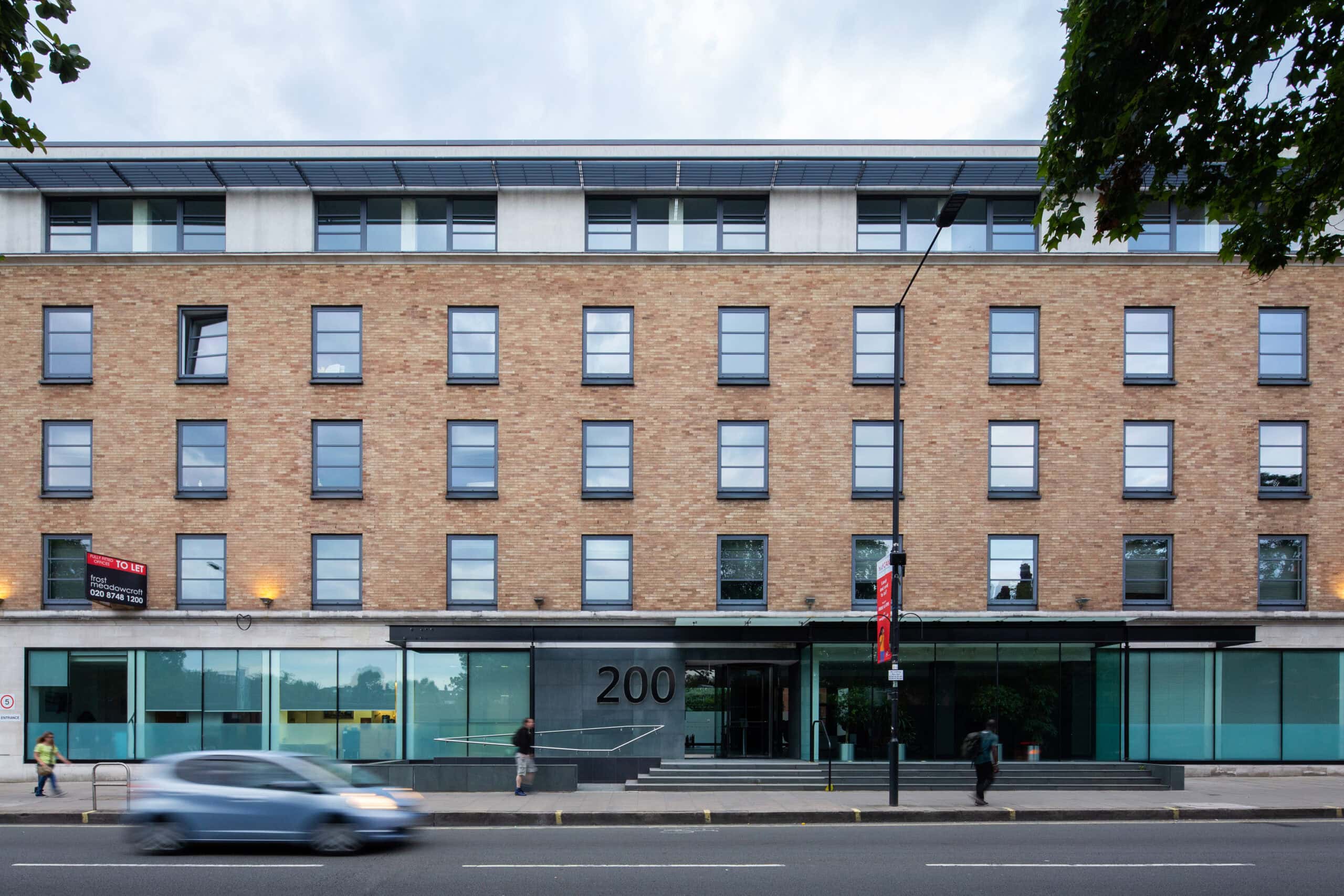 Brick office facade with a glazed ground floor beside the street.