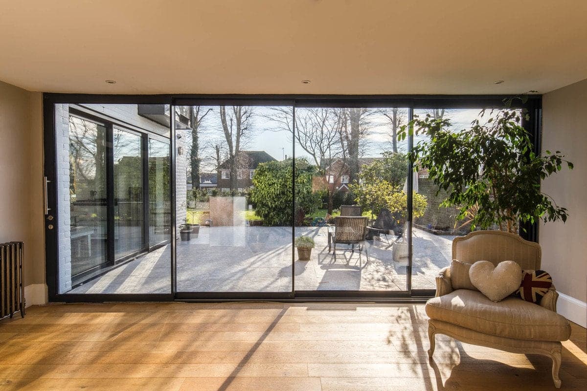 Modern living space blending indoor and outdoor areas with glass wall and patio.