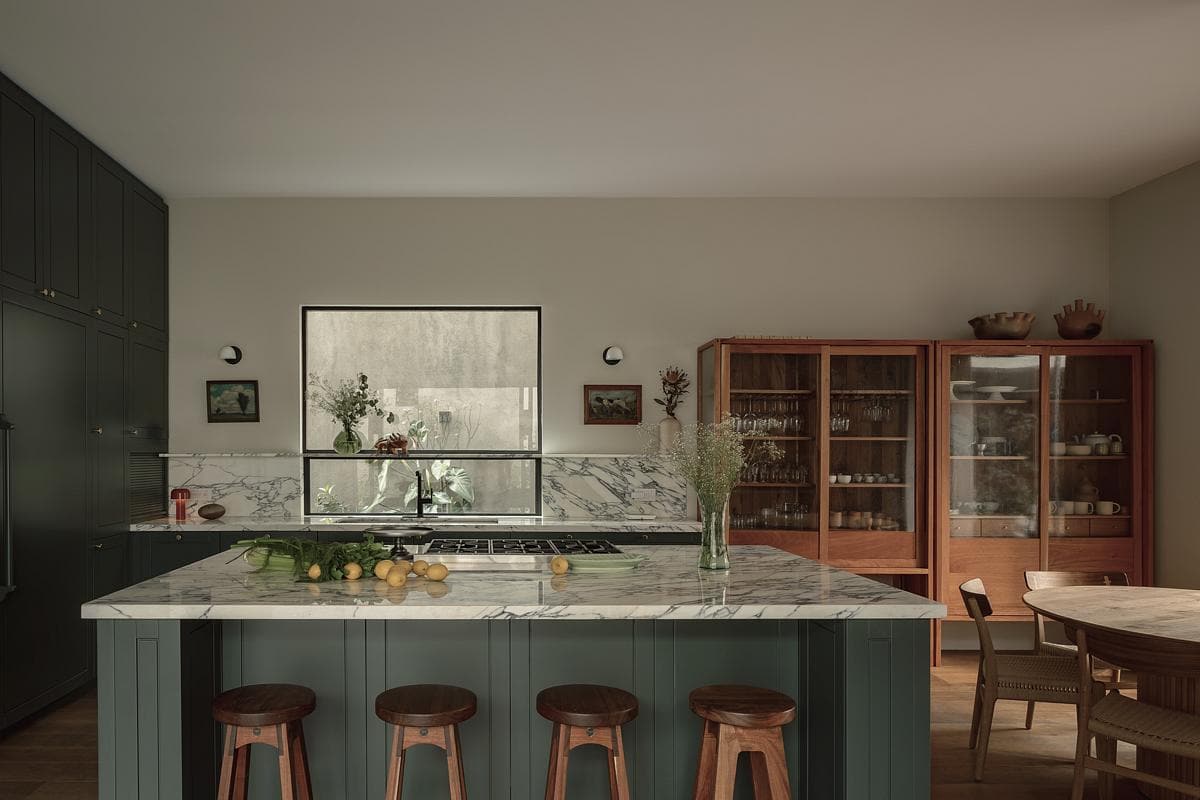 Stylish modern kitchen with marble island, green cabinetry, and inviting natural light.