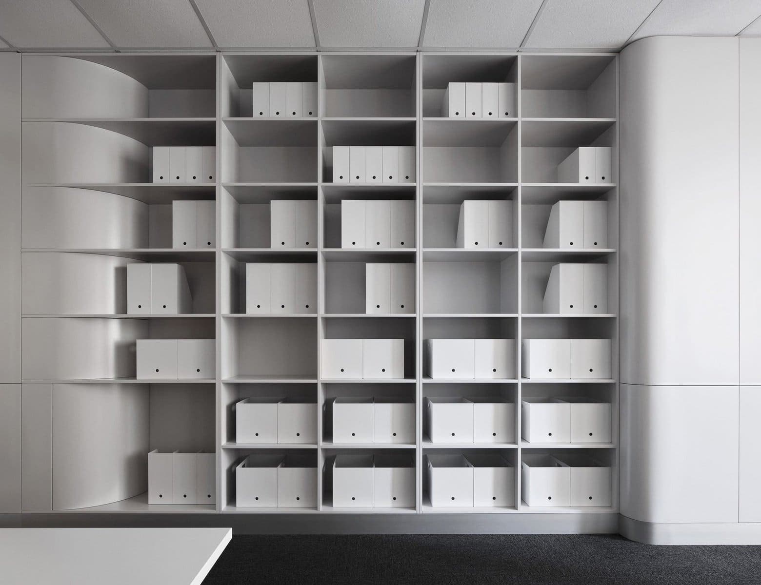 Modern minimalist office with sleek white shelving and organised storage boxes.
