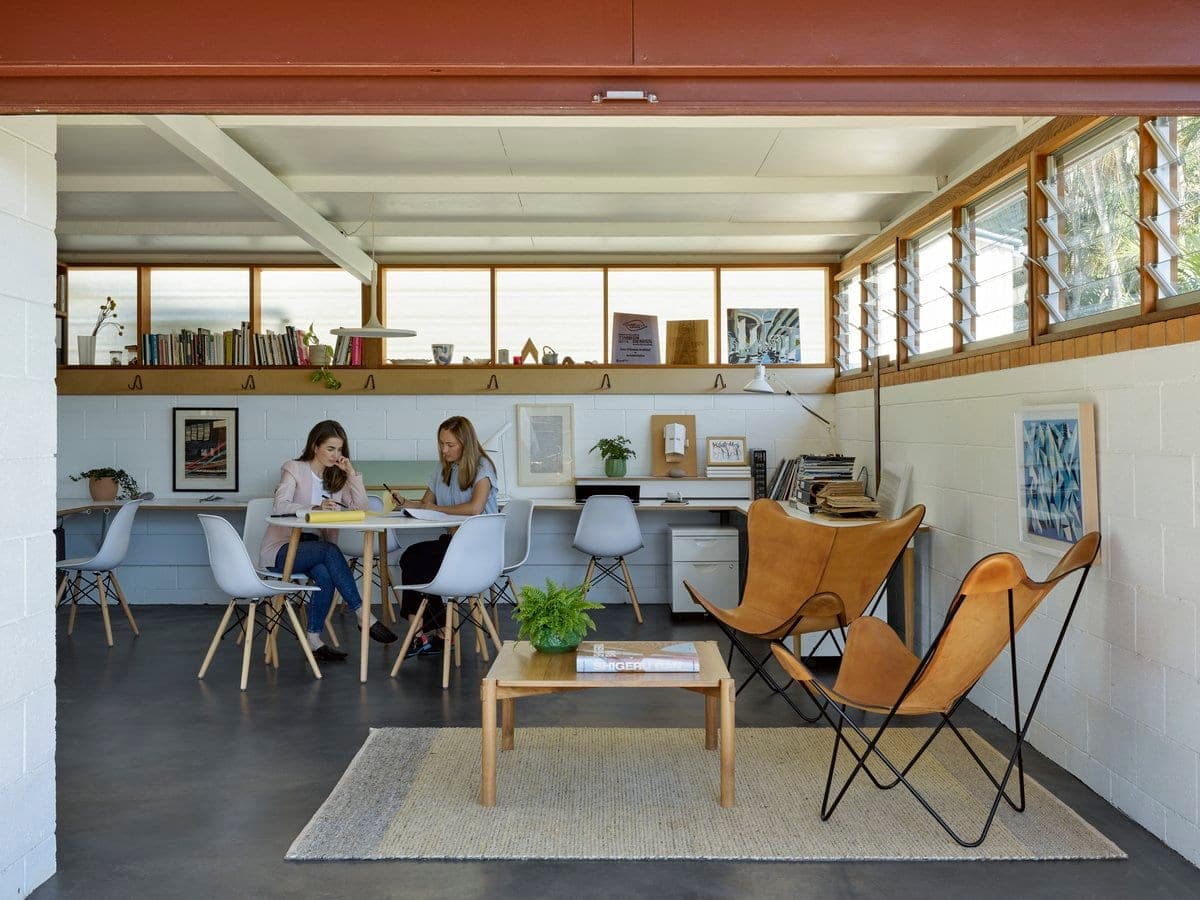 Bright multi-functional room with workspace and cosy living area, featuring natural light and minimalist decor.