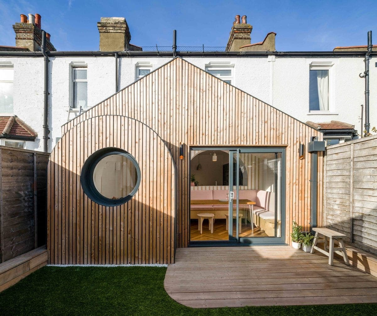 Rear view of a renovated townhouse with modern wooden-clad extension and garden.