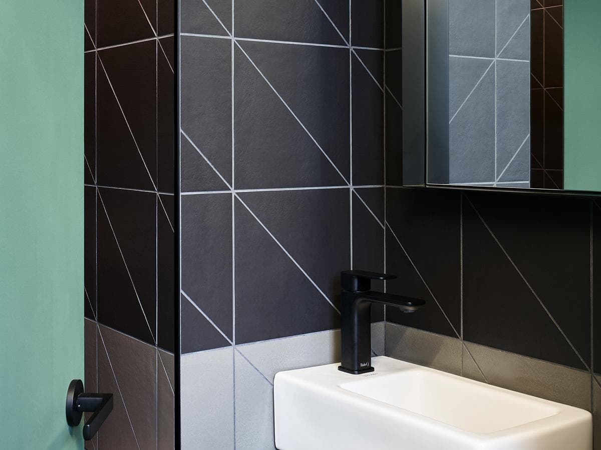 Dark tiled washroom with a compact basin