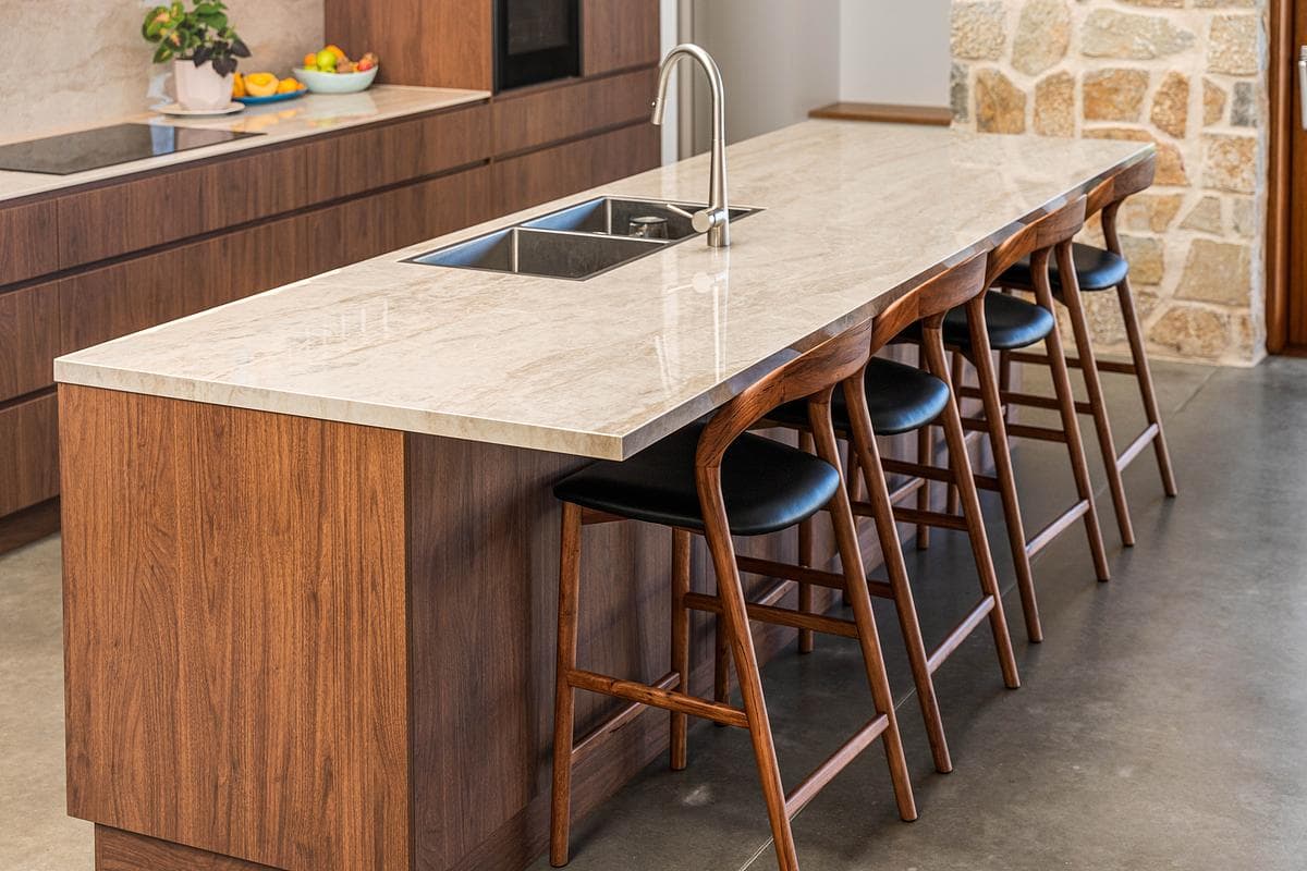 The kitchen island combines timber joinery with a pale worktop.