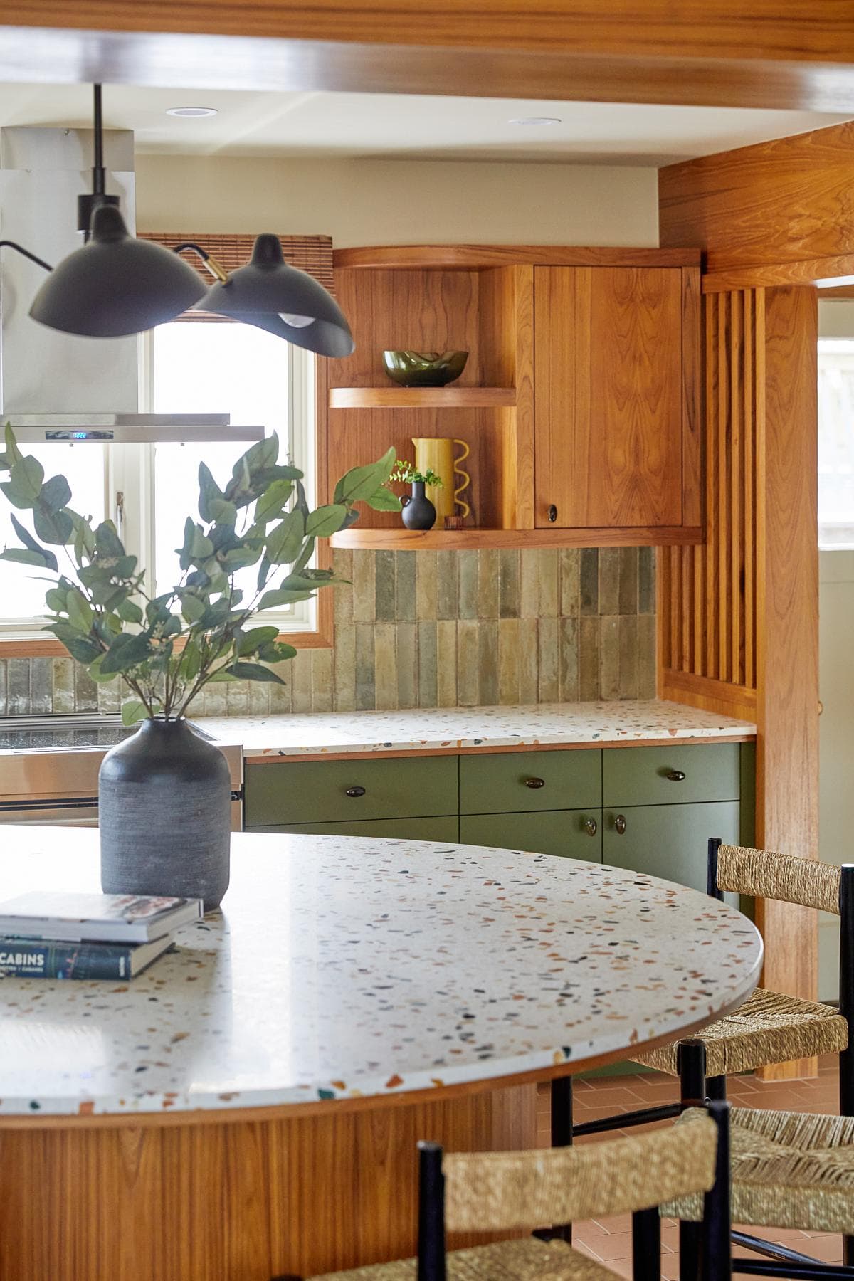 Terrazzo worktops meet olive-green lower cabinets.