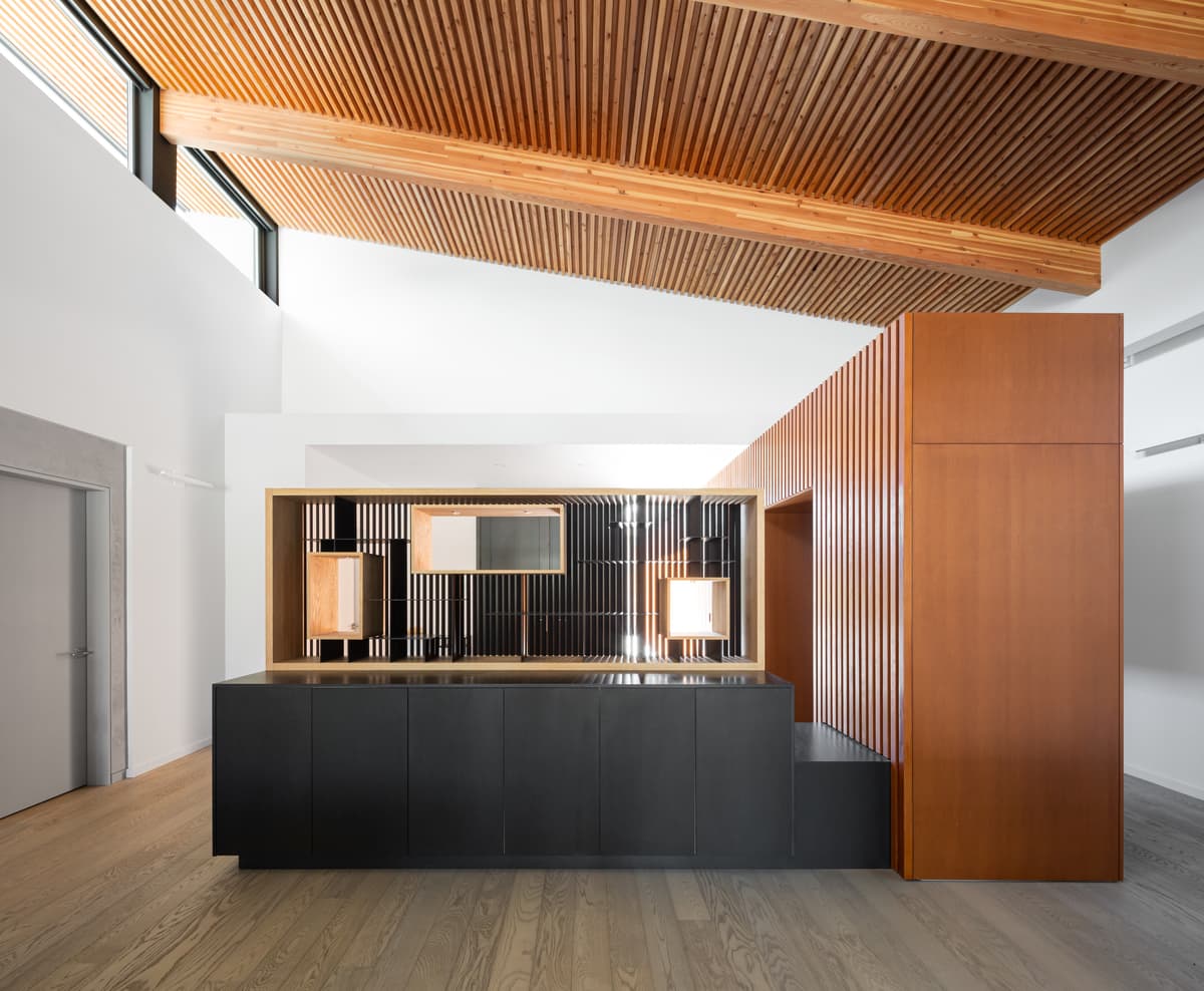 A display cabinet and dark joinery sit beneath the timber ceiling.
