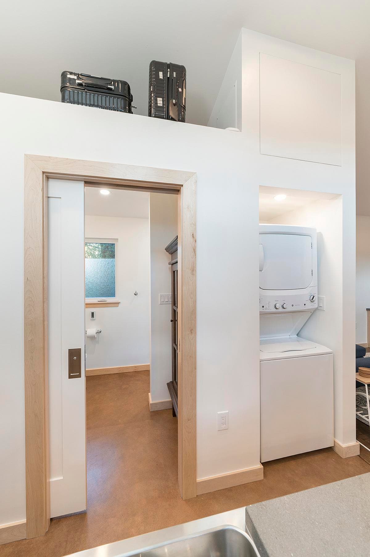 Built-in storage and a stacked laundry area sit beside the bedroom doorway.