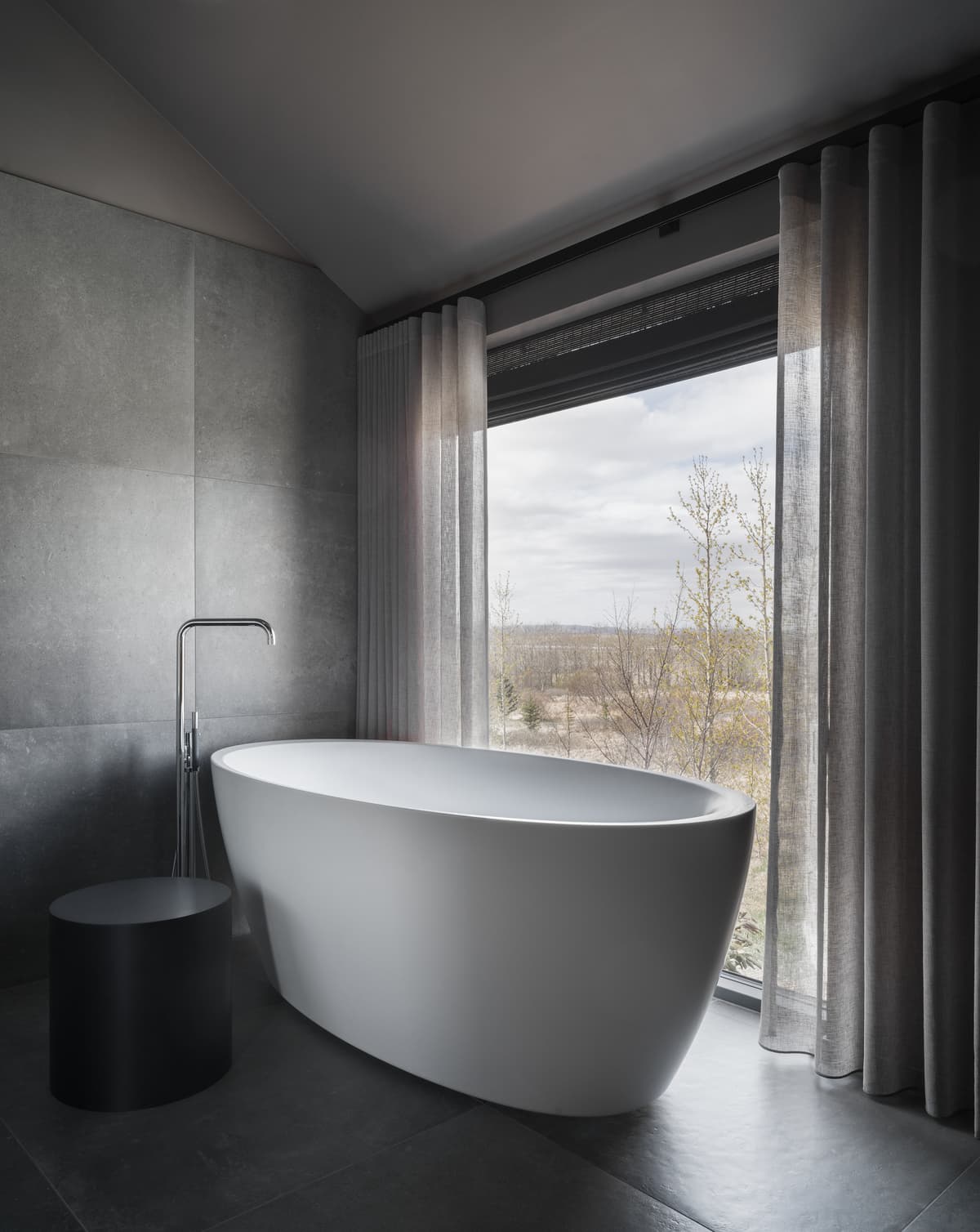 A freestanding bath beside a full-height window.