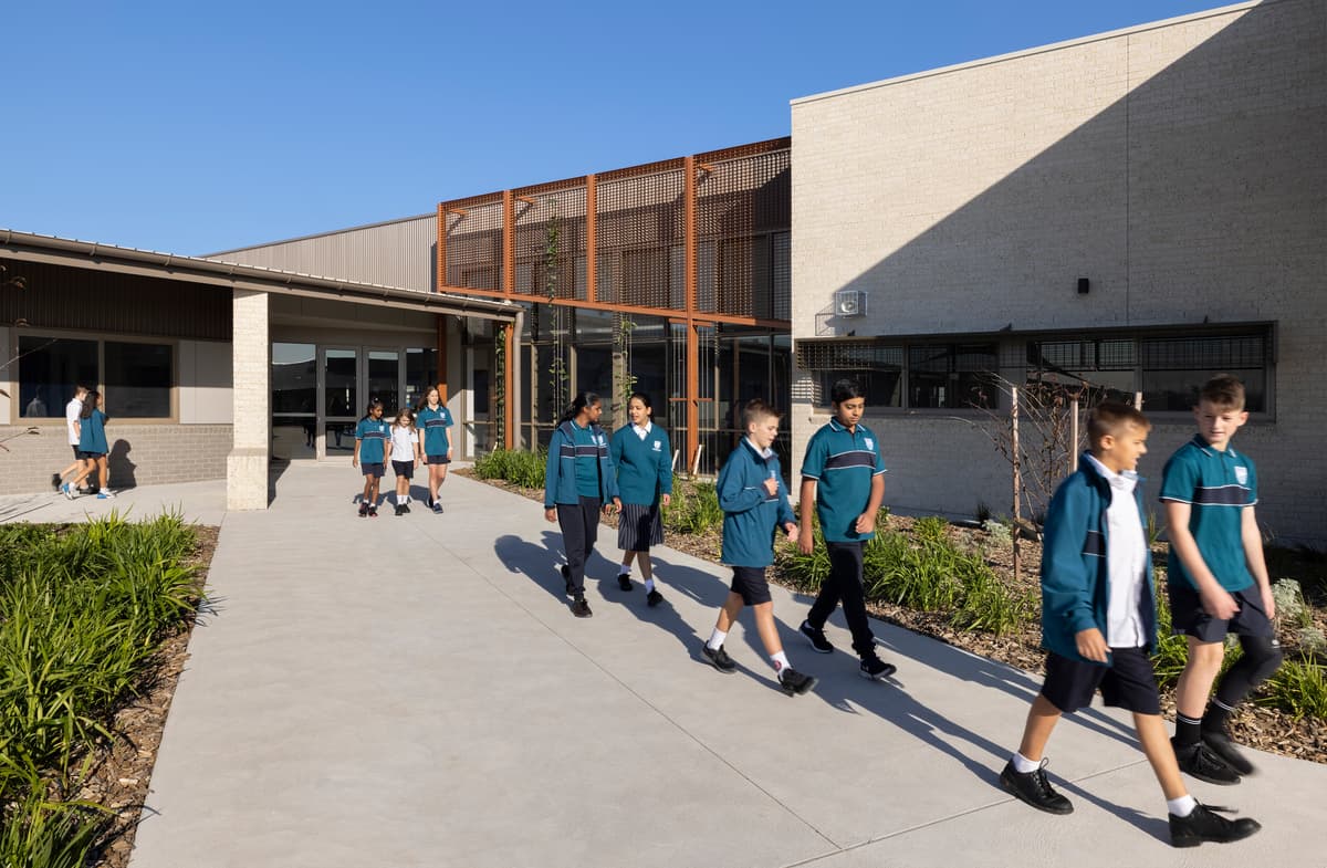 Students walk along a covered path beside the timber-screened building.