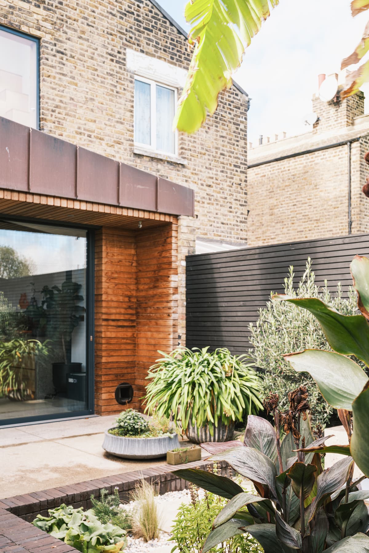 Planting and a sheltered threshold connect the copper-clad extension with the garden.
