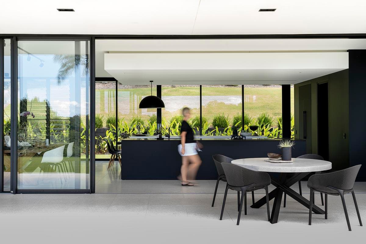 Monochrome kitchen and dining area between glazed walls.