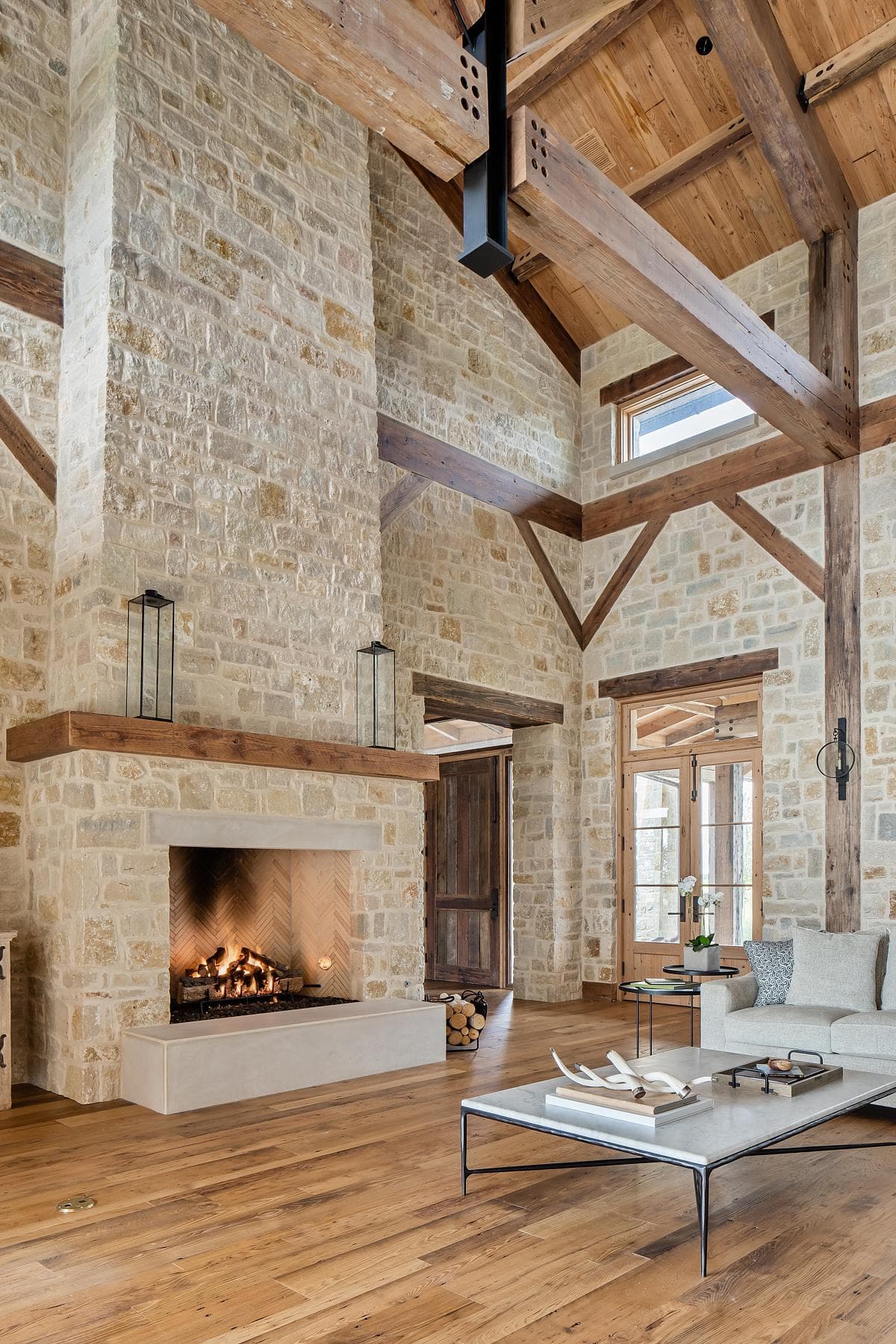 A stone fireplace beneath exposed timber roof beams.
