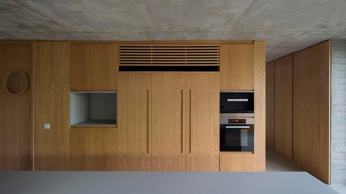 Long timber kitchen wall set within the concrete interior