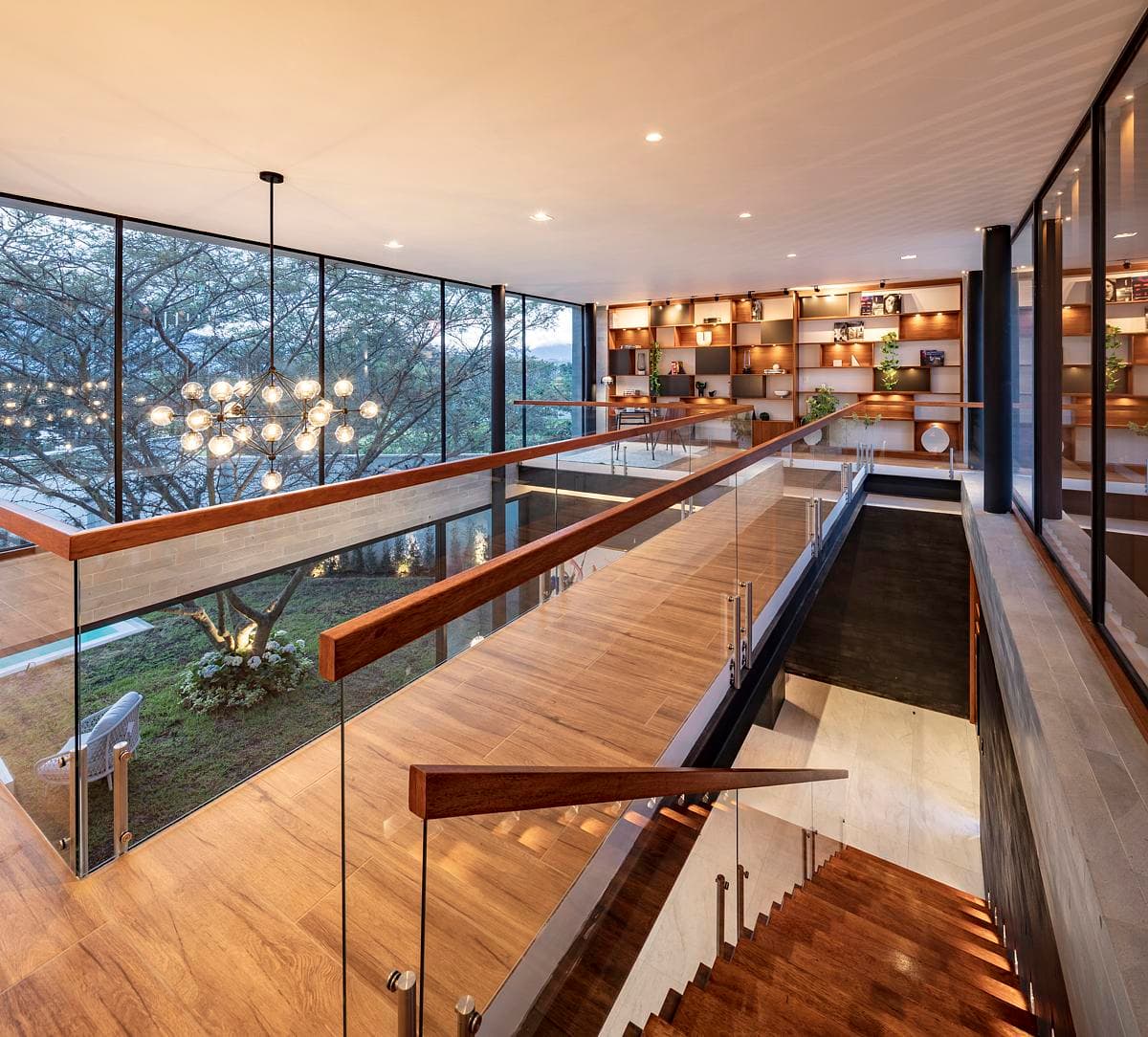 An upper-level gallery looks across the living area towards the trees.