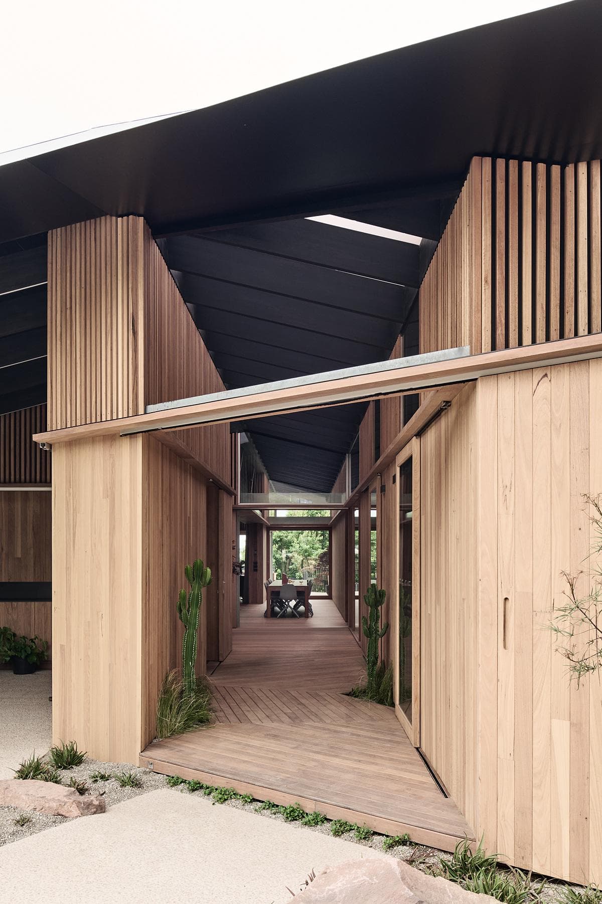 Cross-shaped breezeway connecting timber-clad pavilions
