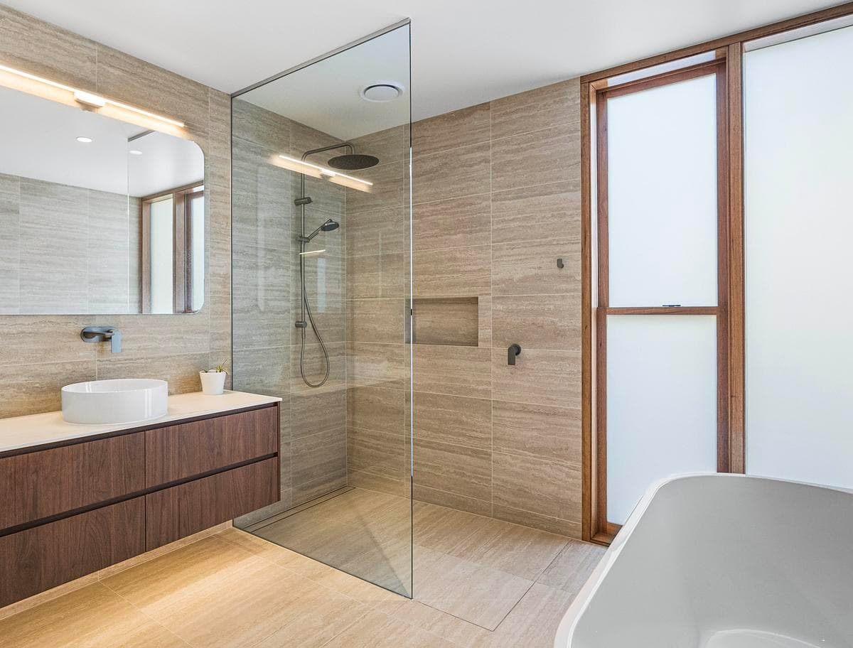 Timber joinery and stone finishes continue into the bathroom.