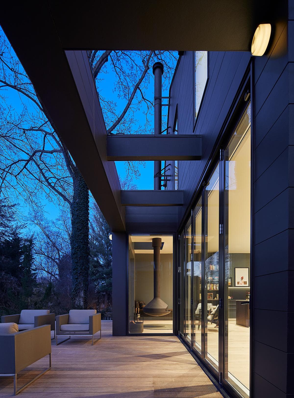 Covered rear terrace beneath the steel-framed addition at dusk.