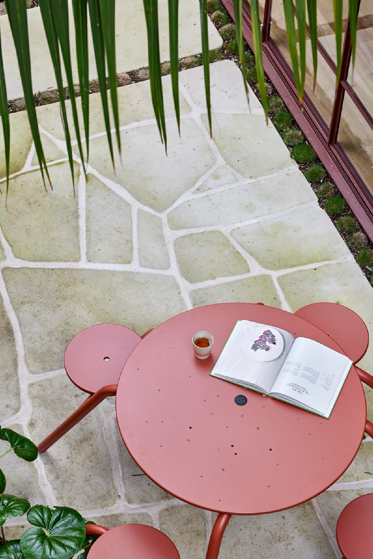 Pink courtyard table beside stone paving and planting
