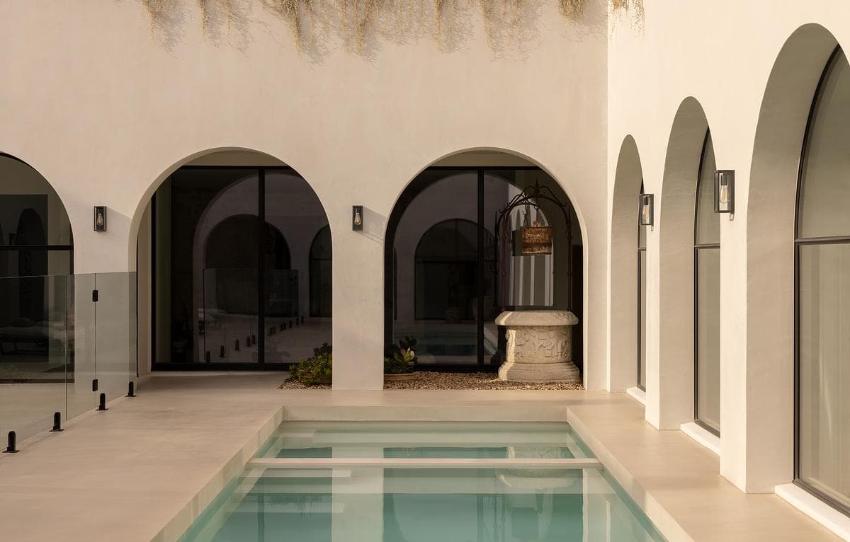The courtyard pool sits between the pale arches of the loggia.