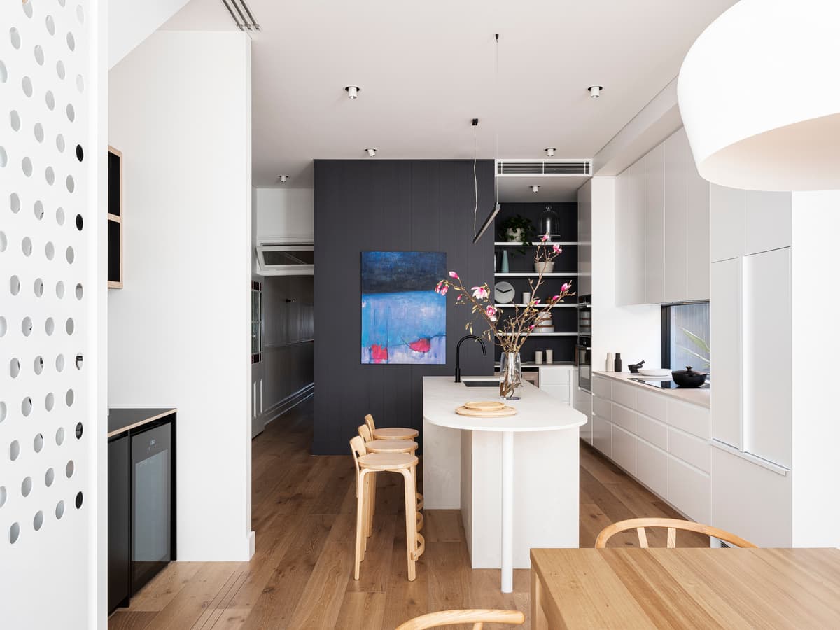 Curved joinery and a timber floor connect the kitchen and dining spaces.