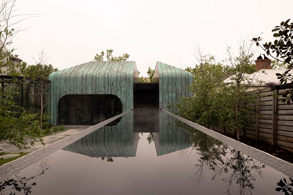 The elevated lap pool extends towards the curved copper pavilion.