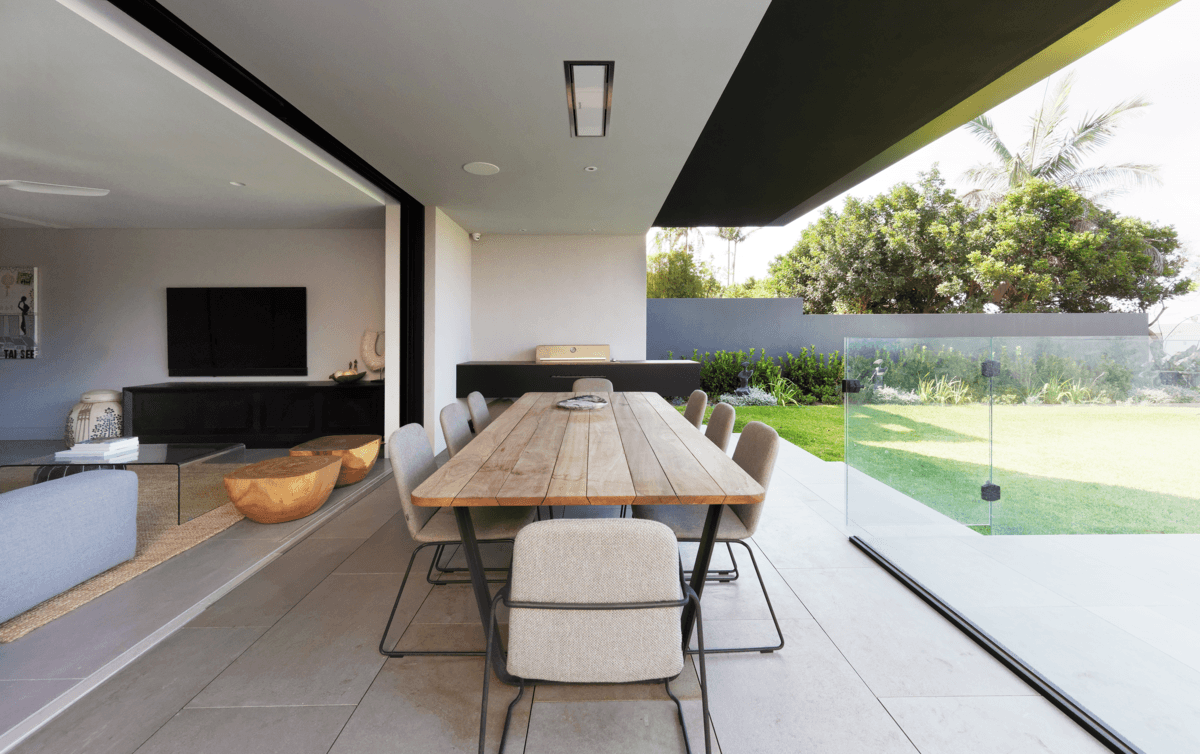The covered outdoor dining space opens towards the garden and pool.