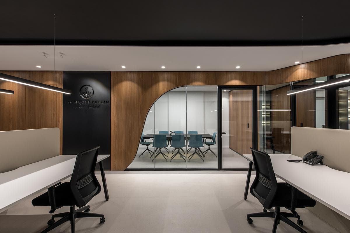 Curved timber cladding frames a glazed meeting room beside the open desks.