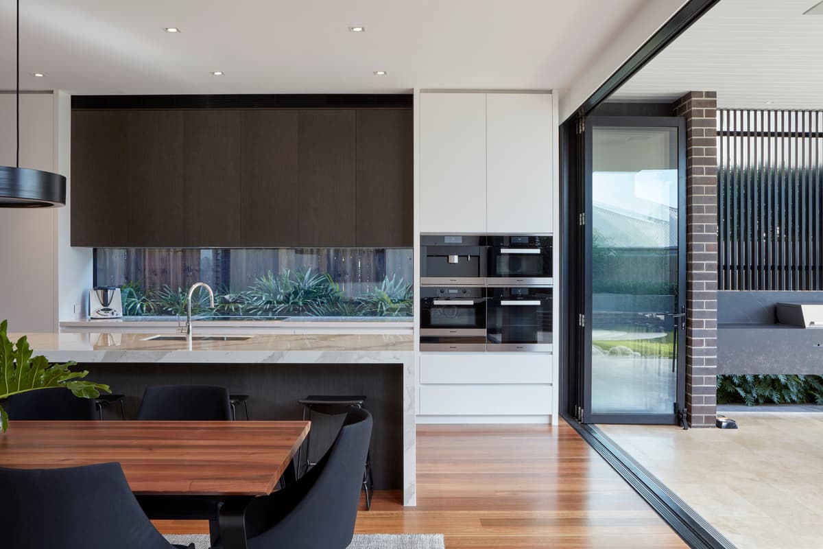 The kitchen sits beside an opening to the outdoor dining area.