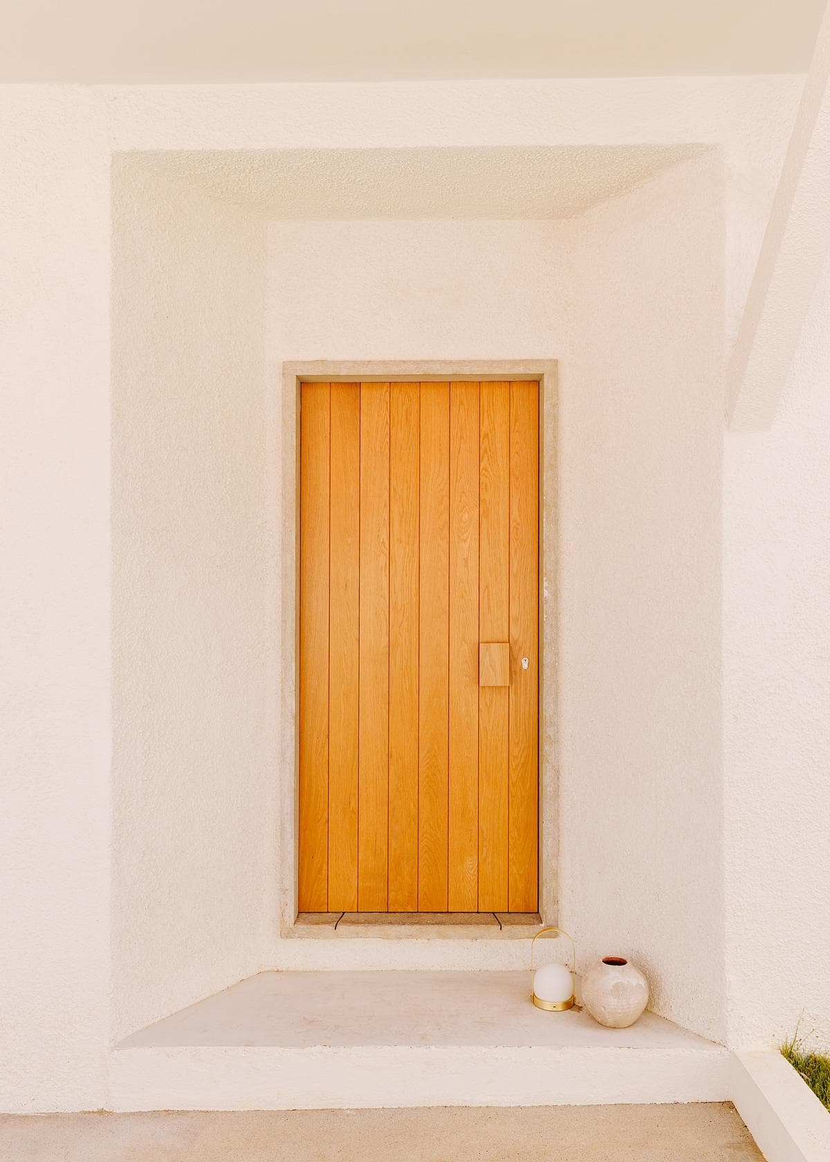 A timber door set within a pale entrance recess.
