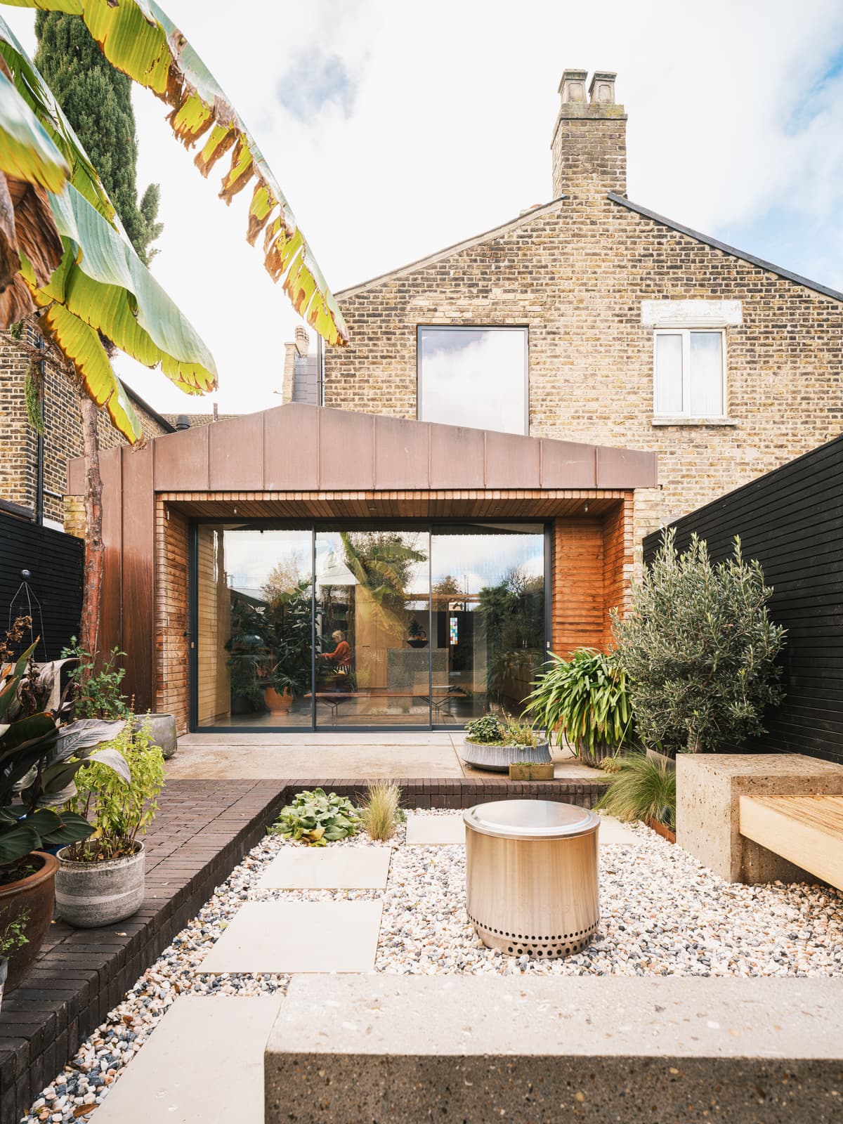 The copper extension opens onto a planted garden and gravel seating area.
