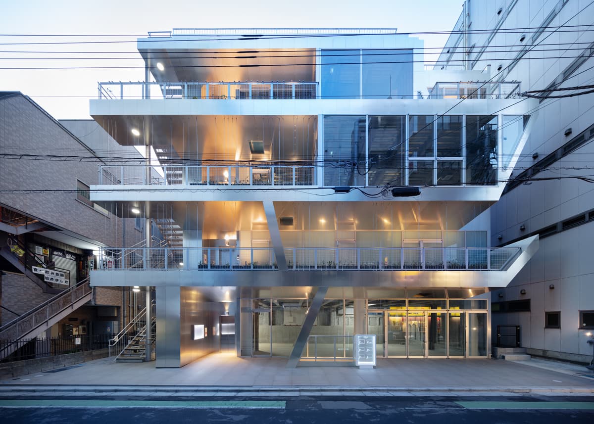 The street façade at dusk, with occupied terraces visible behind the metal frame