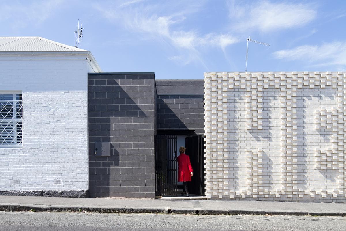 Dark blockwork frames the entrance beside the white HELLO wall.