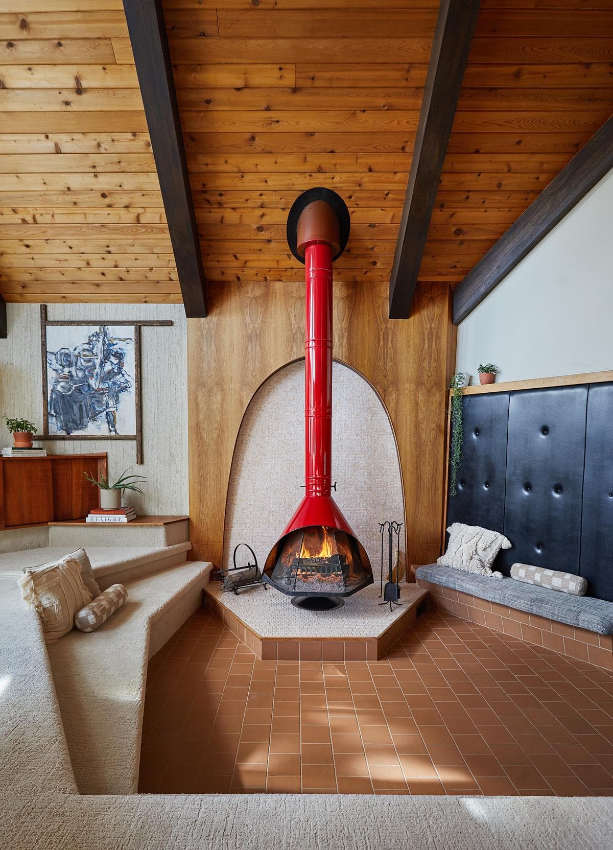 A red stove in the sunken fireplace area.