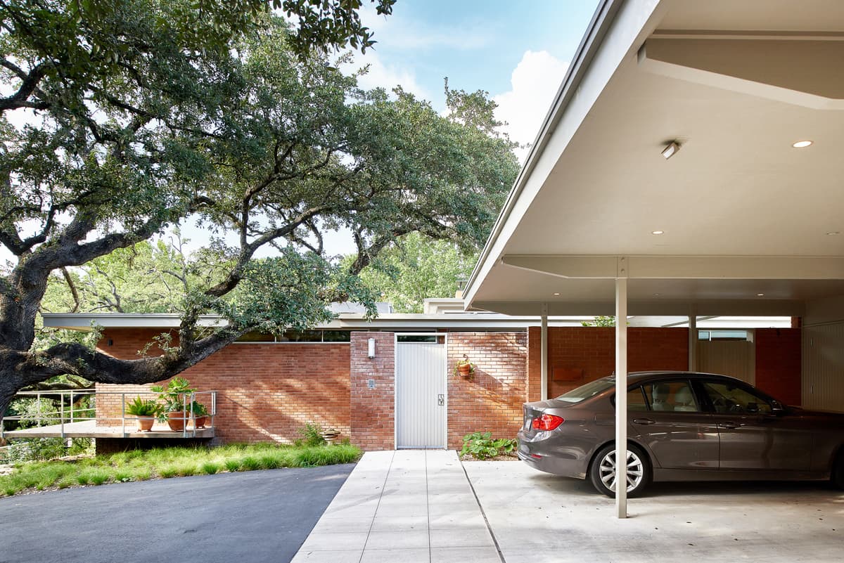 The carport and low brick walls retain the house’s horizontal character.