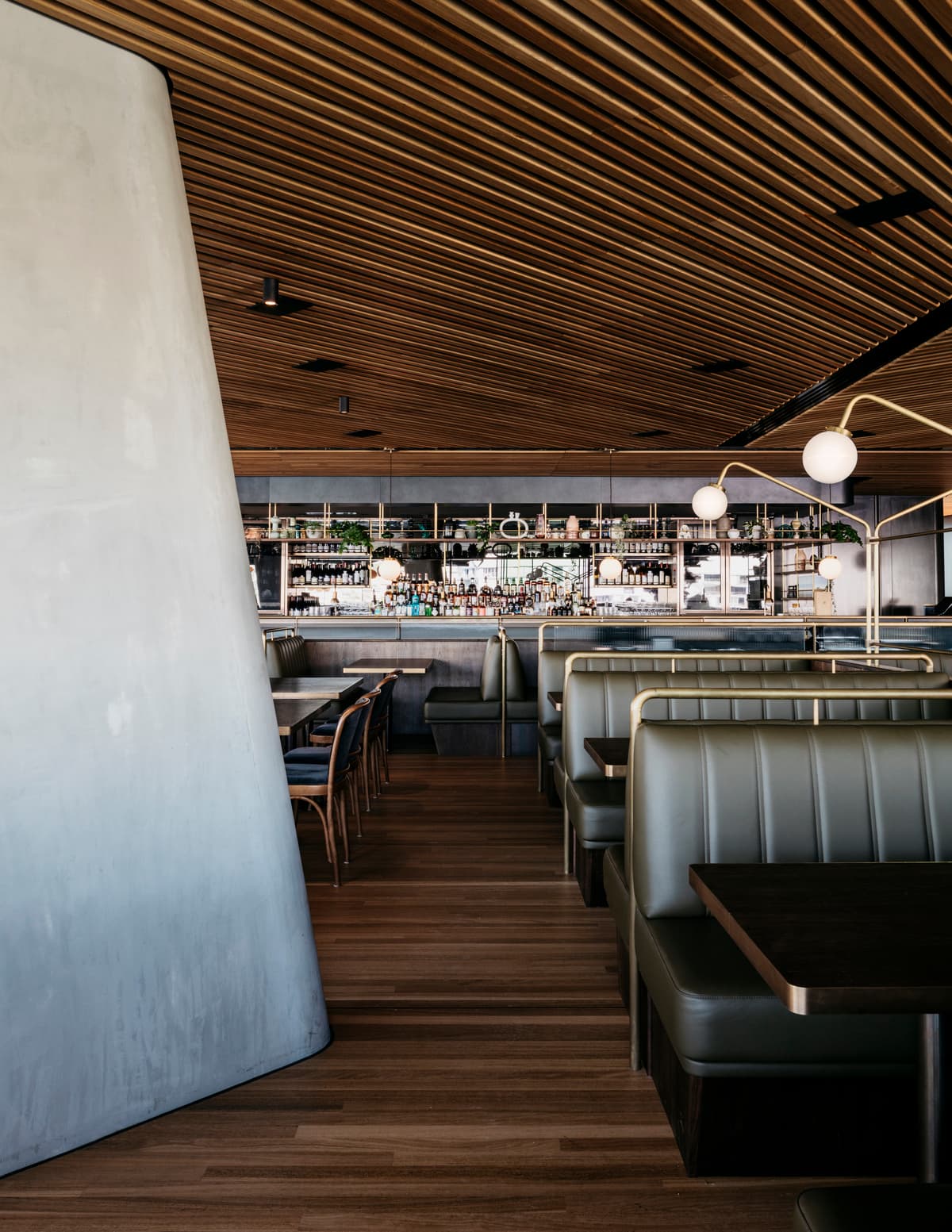 Curved seating and a timber ceiling organise the dining space.