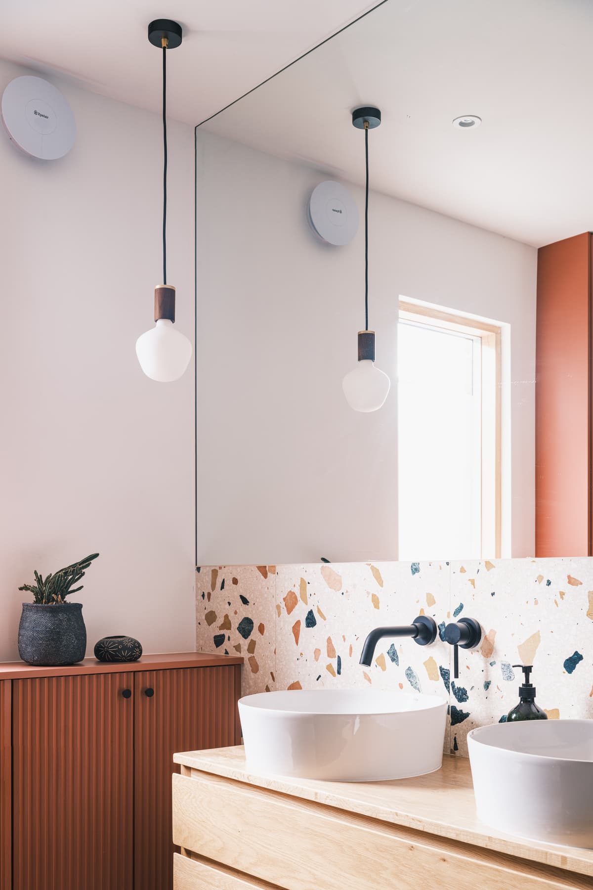 Terrazzo surfaces and warm paint tones distinguish the bathroom.