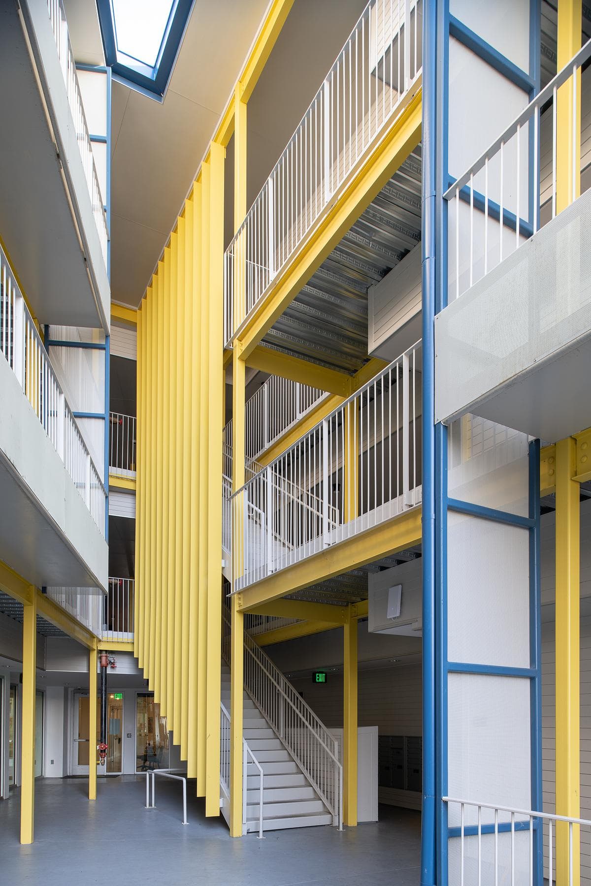 Open stair and bright yellow columns beside external corridors