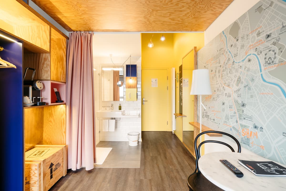 Yellow joinery and a pink curtain frame the route between the room and bathroom.