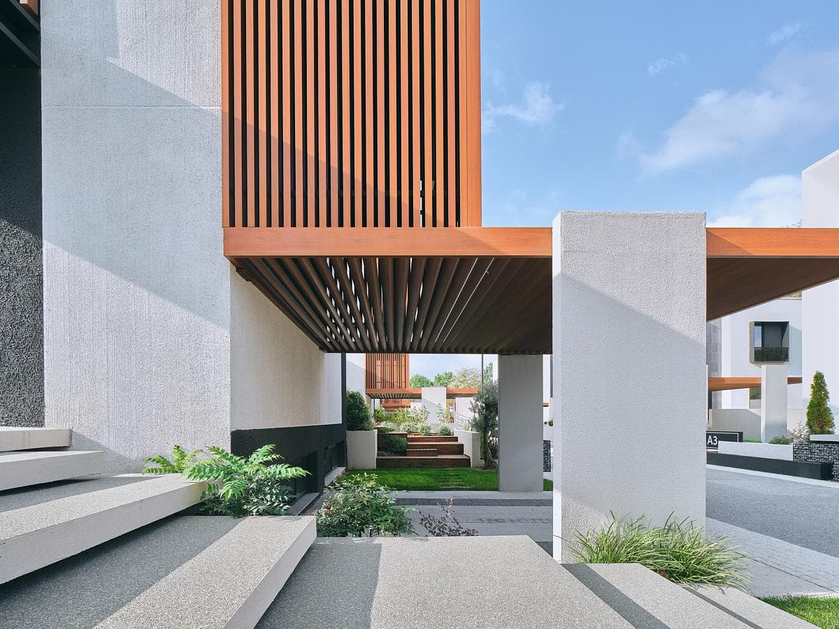 A covered passage runs beneath a projecting slatted volume.