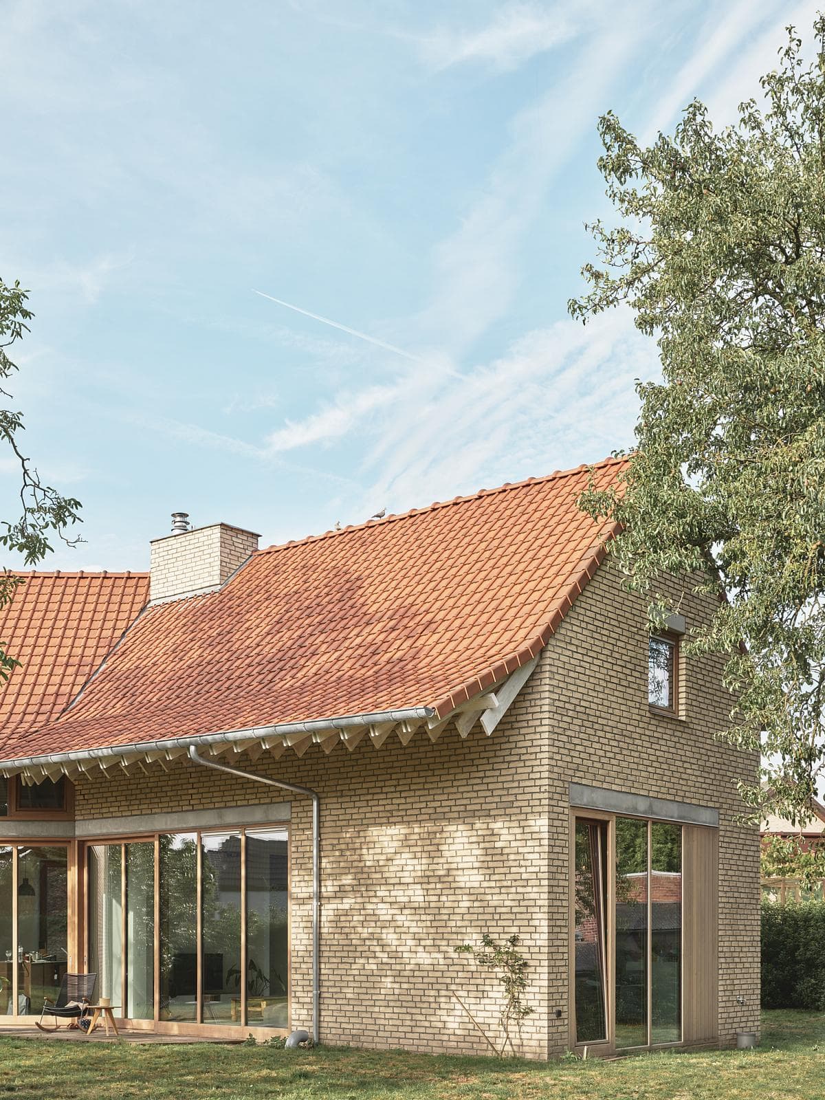 Brick chimney and tiled roof seen through the garden