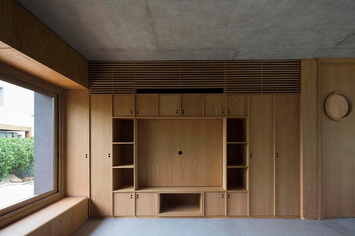 Oak joinery wall with integrated storage and a ventilation grille.