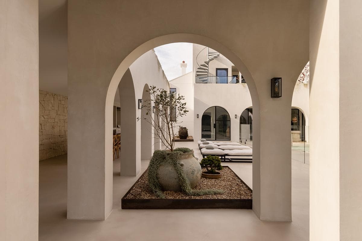 An arch frames the planted courtyard and pool beyond.
