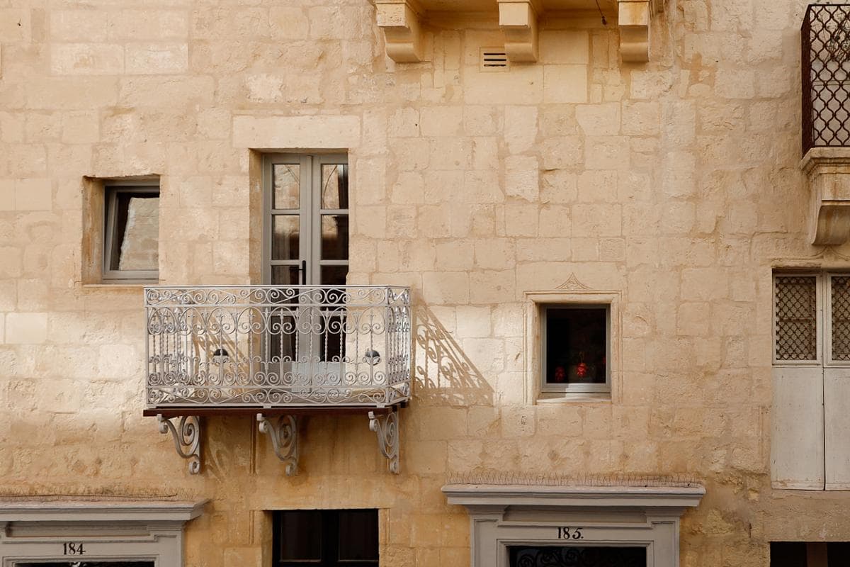 The restored limestone facade retains the building’s traditional balcony and window openings.