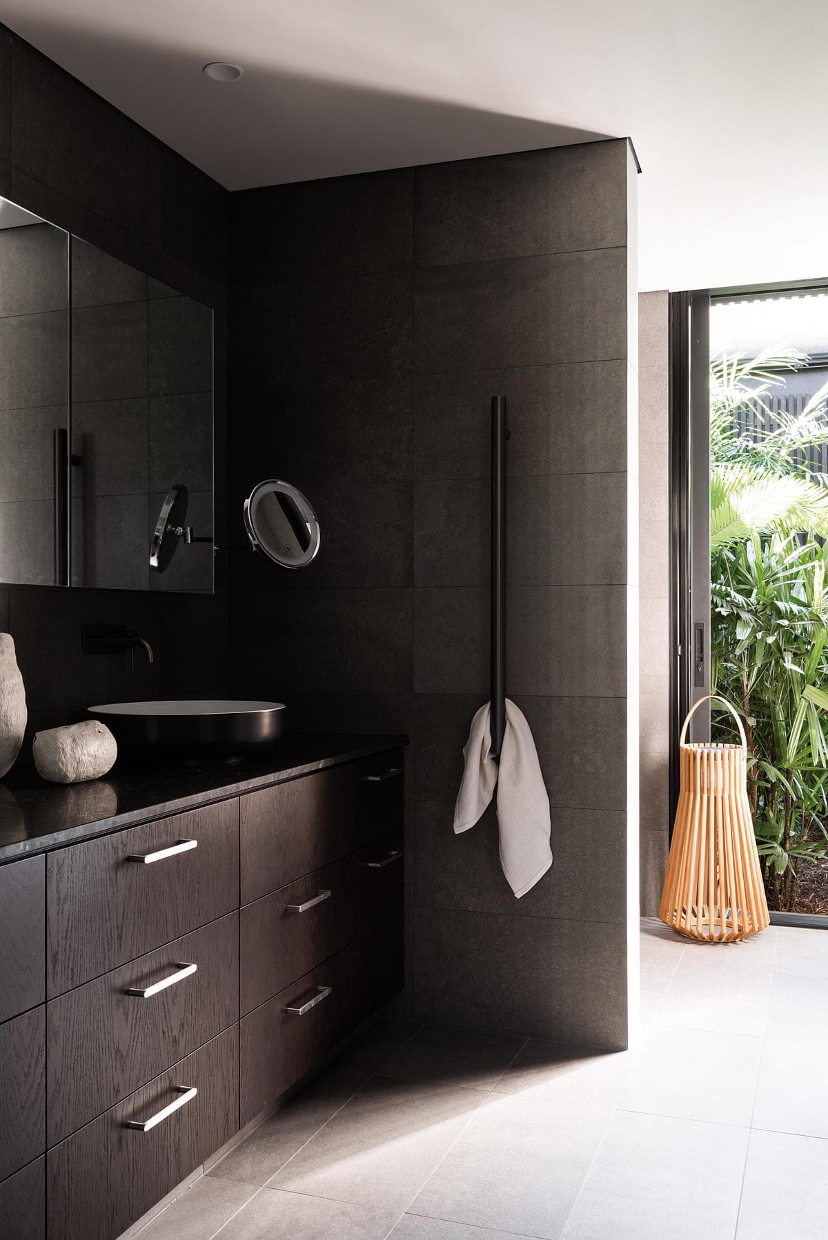 Dark joinery in the bathroom, opening towards courtyard planting.