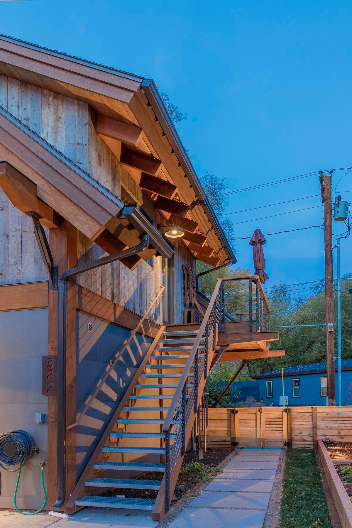 An external timber stair connects the garden and upper deck.