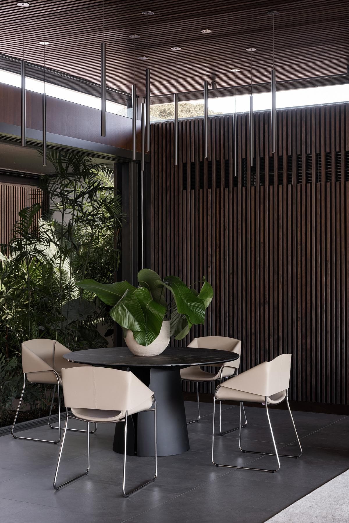 Dining table beside timber screens and planting.