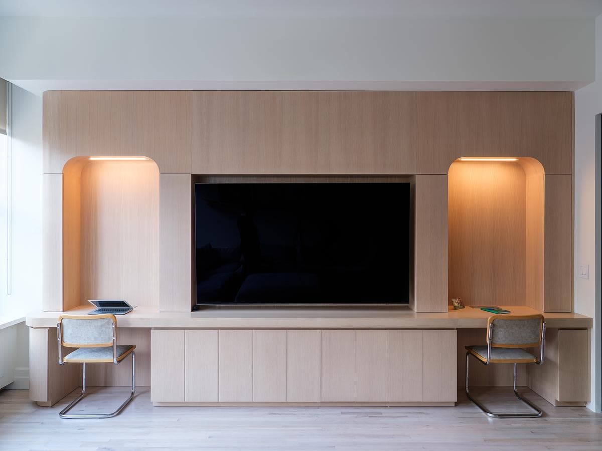 Pale timber media wall with lit niches and a built-in desk.