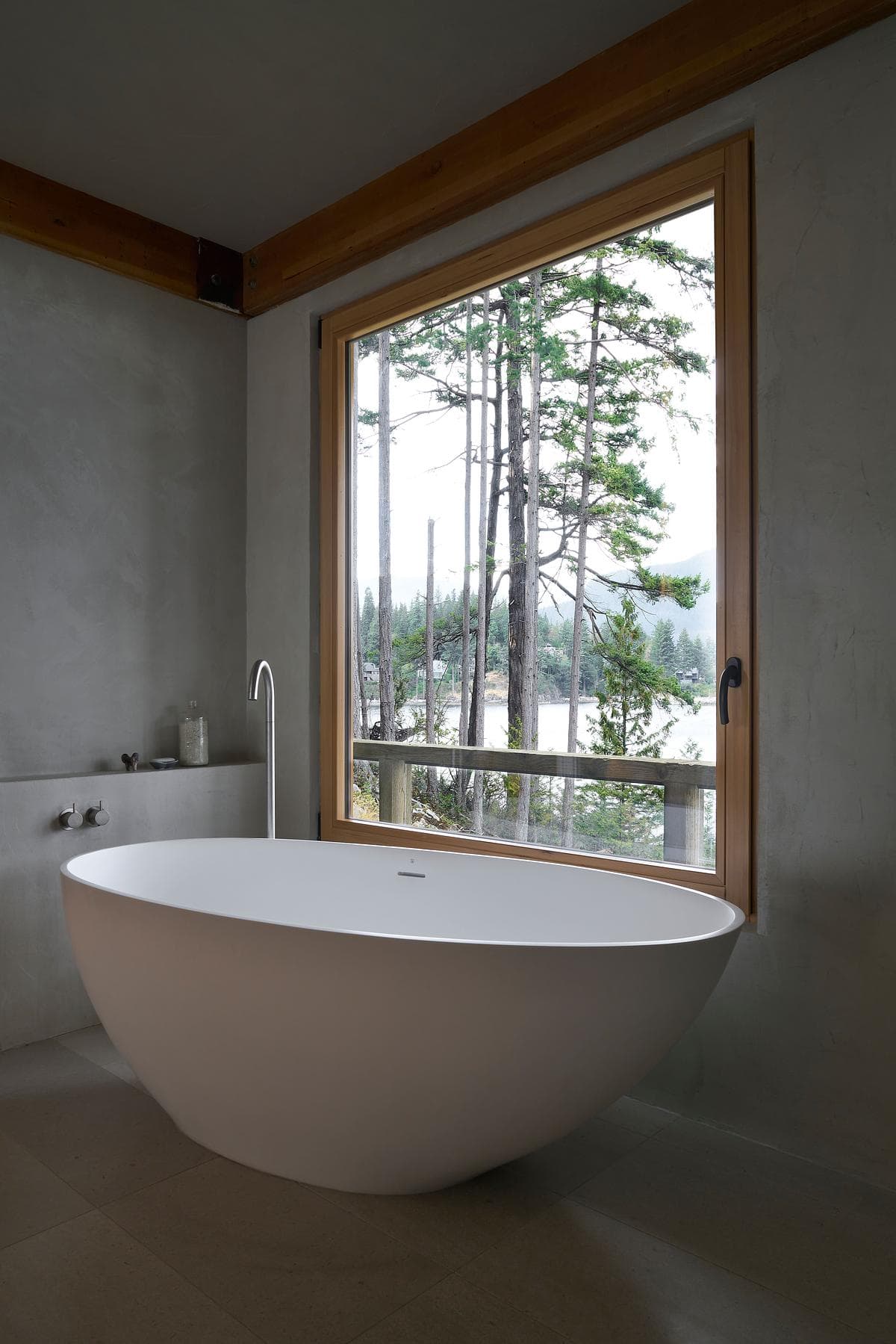 Freestanding bath beside a window facing the trees